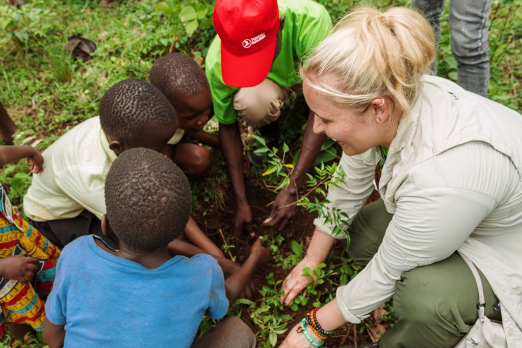 Janelle Nightingale planting a sapling with children in Uganda